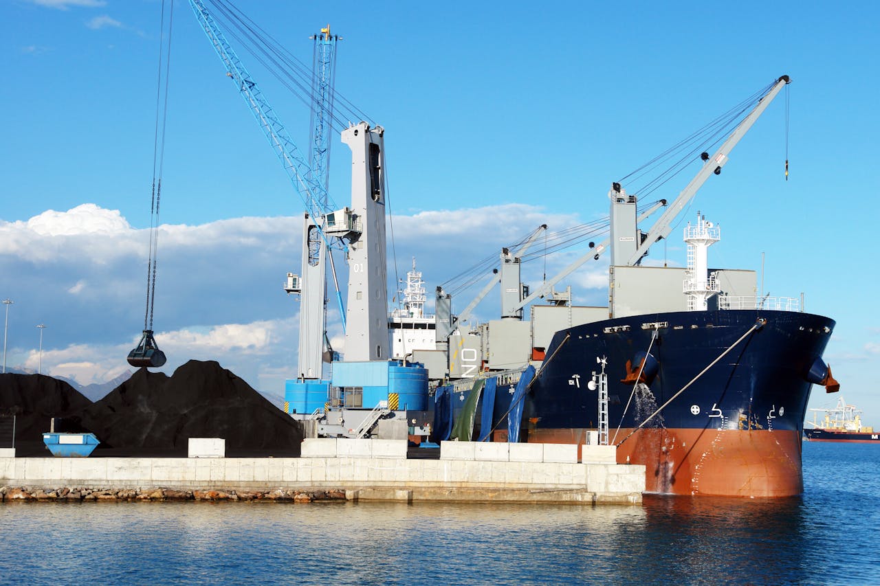 Crafting Captivating Headlines: Your awesome post title goes here Cargo ship and cranes at an industrial port, loading minerals under a clear blue sky.